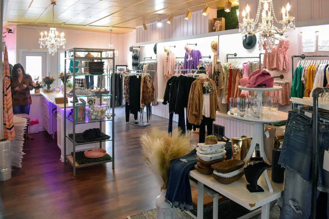 Bright boutique interior with crystal chandeliers, pink décor and styled clothing racks